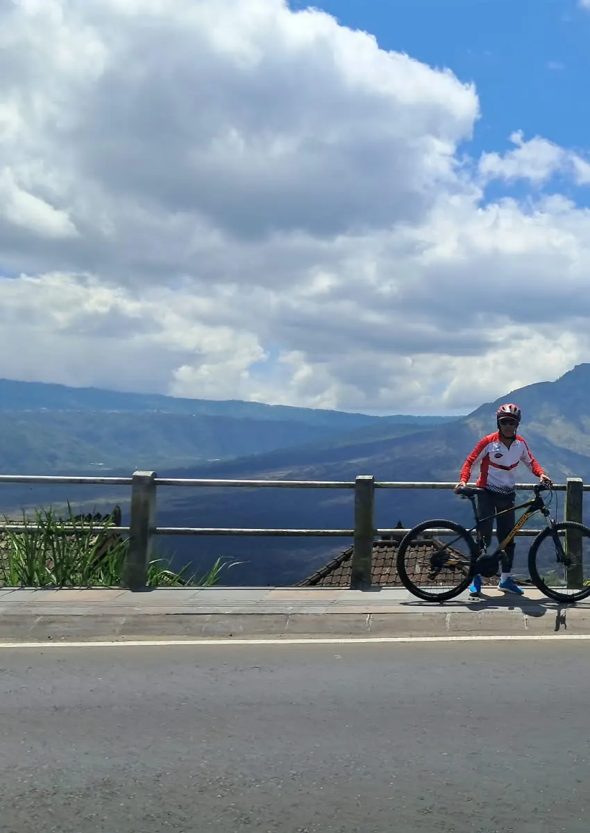 Cyclist with his bike at a viewpoint facing the Kintamani mountains