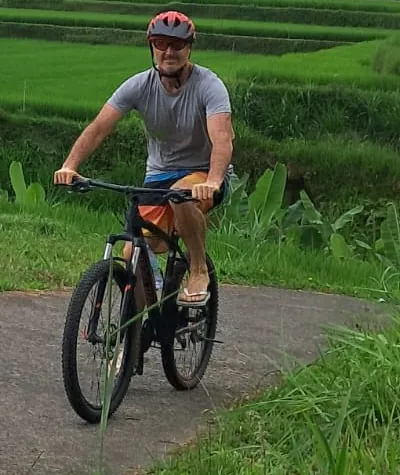 Guest cycling on a path between green rice terraces